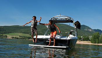 lake boat on a lake with kids jumping off the back into the water