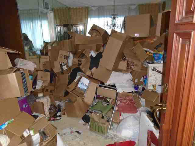 before picture of a hoarded dining area filled with boxes and trash