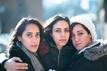 3 sisters close together looking sad from tragedy