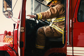 fireman reaching to close the door of his fire truck