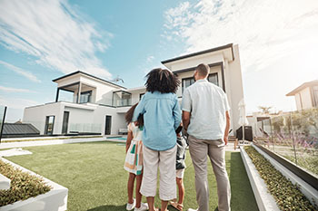 a couple and their two children looking at their new home. homeowners at last