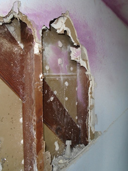 wall with cut out drywall and purple tear gas residue