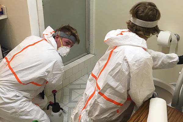 biohazard technicians in biohazard suit cleaning a bathroom after a death