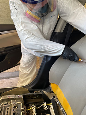 biohazard technician cutting out biohazards froma a car seat