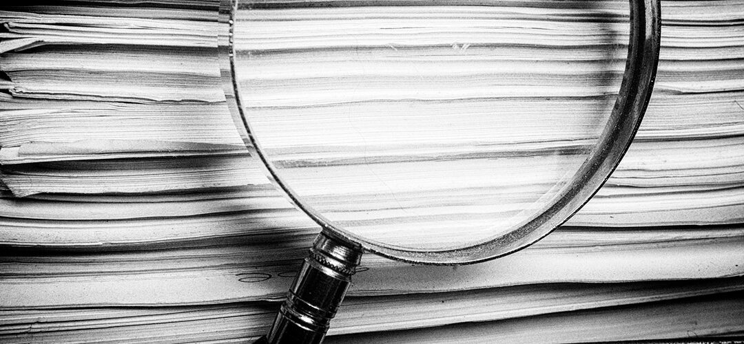 stack of documents with a magnifying glass
